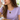 Woman in a lavender tee wearing the gold figaro chain necklace with a black enamel charm medallion pendant