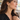 Woman in a black V-neck blouse wearing gold flower crystal earrings