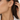 Close-up of a gold paper clip drop earring with a white shirt