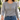Woman wearing the gold paper clip lariat necklace with crystal lock over a gray sweater and jeans
