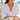 LIZOU green enamel fish charm necklace worn with a white linen shirt on a beach chair