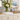 Scalloped acrylic napkin holder on white sideboard with flowers
