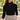 Silver open link charm necklace worn at the collarbone with a black mock neck top and beige trousers