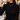 Woman wearing the silver open link charm necklace over a black ribbed mock neck top at a cafe